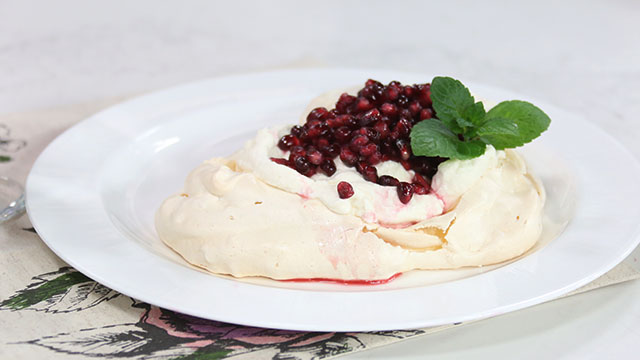 Heart shaped pavlova with pomegranates and whipped cream